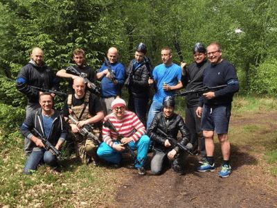 Polterabend-hold samlet i skoven med geværer, brudgommen udklædt forrest
